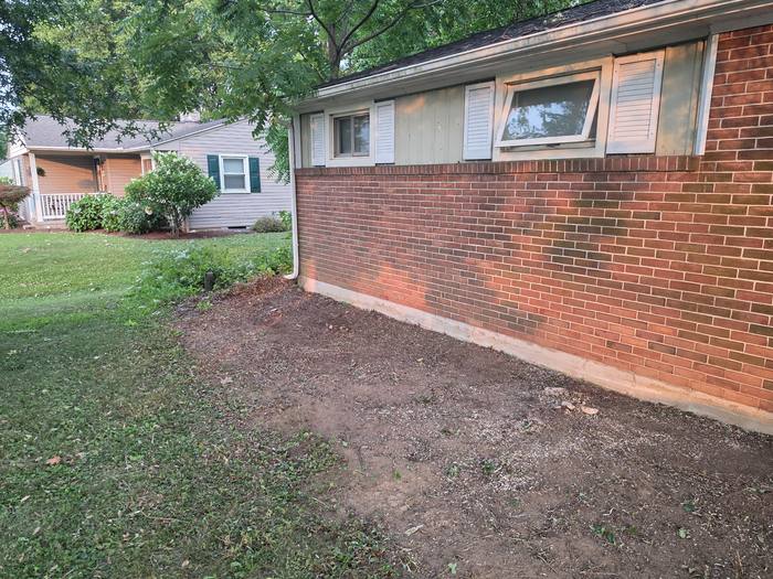 Bare graded soil along a brick wall before deck framing begins — Richland, PA